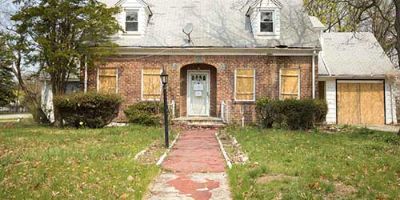 A Foreclosed Property with an Overgrown Yard and Boarded Windows.
