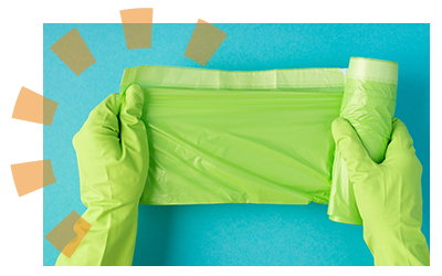 A person wearing green rubber gloves holding a roll of green, plastic trash bags.