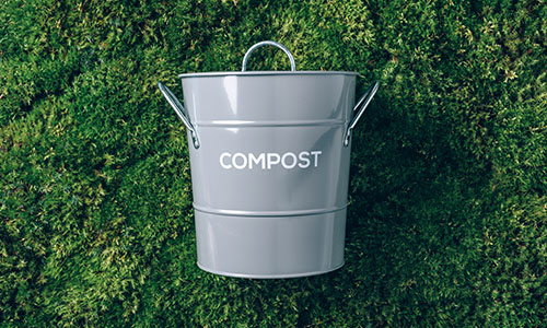 Grey compost pail on city grass to be used in food waste collection program.