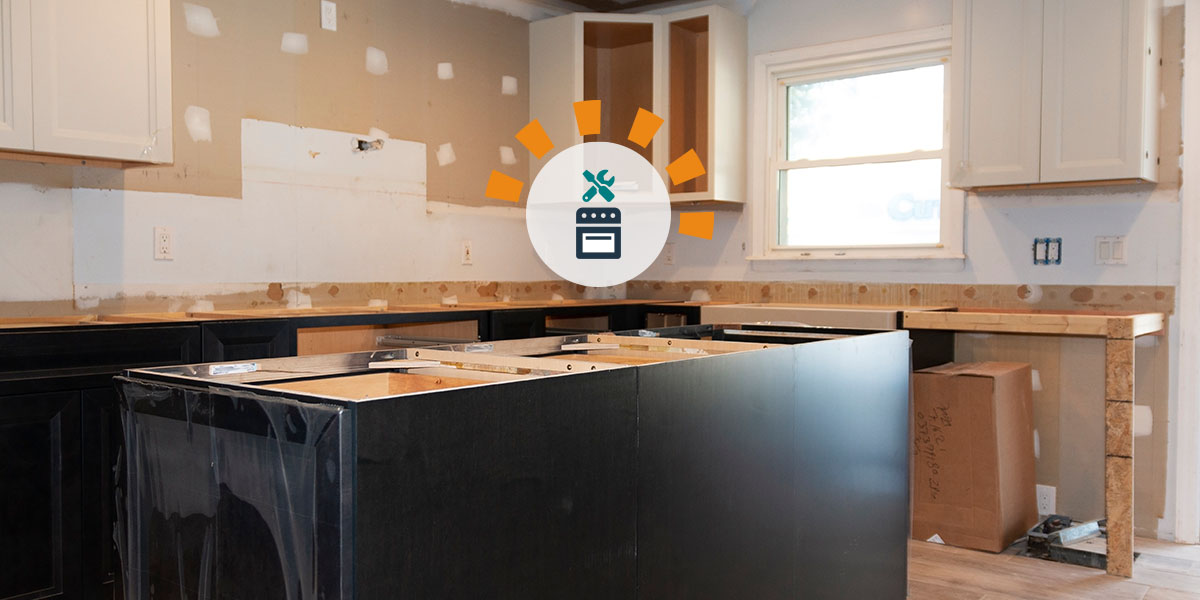 A gutted kitchen with empty cabinets and patched walls. 