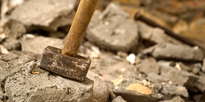 A metal hammer near broken up concrete.