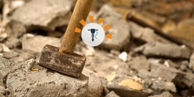 A metal hammer near broken up concrete.