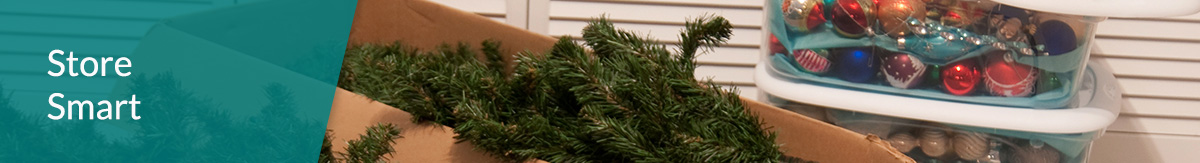 A broken down artificial tree in a cardboard box with ornaments in storage tubs.