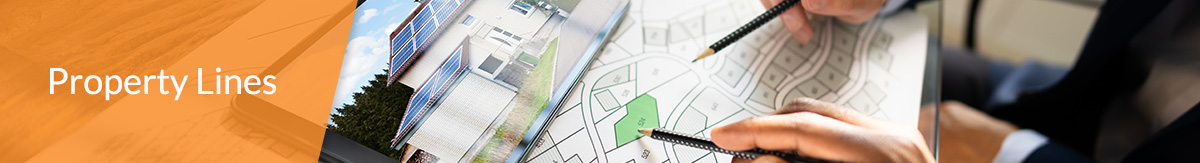 Two homeowners hands with pencils on a blueprint looking at property lines for home addition.