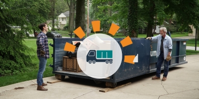 Two men standing near a loaded roll off dumpster in a driveway.