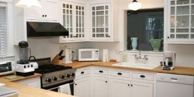 Kitchen With Wood Countertops and White Cabinets