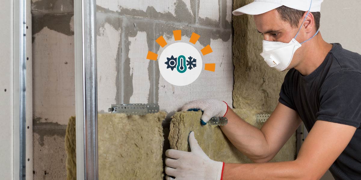 Man in a mask installing insulation in garage.