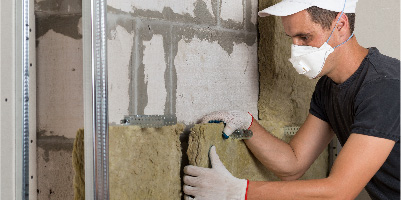 A man in a mask installing insulation. 