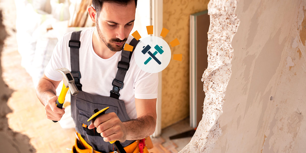 Man knocking down a wall with tools for an open concept living room.