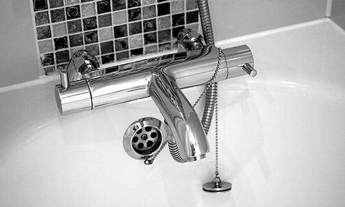 A chrome bath fixture on white bathtub.