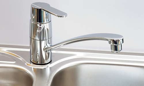 A stainless steel faucet on a metal sink. 