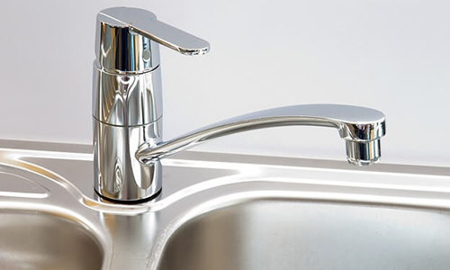 A stainless steel faucet on a metal sink.