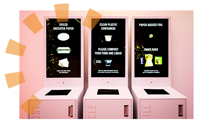 Three pink EvoBin trash receptacles with digital readouts showing what material is accepted in the can.