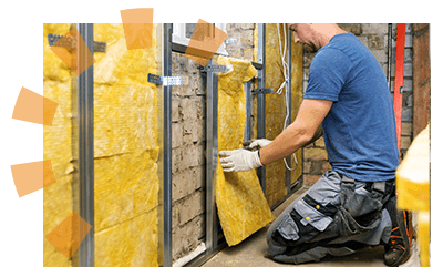 Man installing fiberglass insulation between basement wall studs.