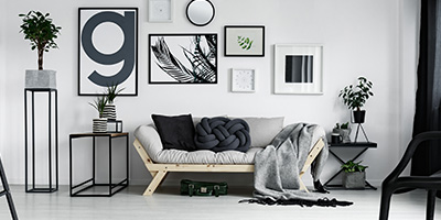 Black, white and grey living room designed with sofa, chair, tables, artwork and plants by interior decorator for blog website.