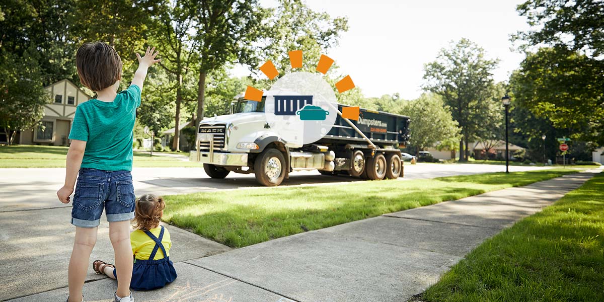 Kids waving at roll off dumpster driver during delivery to driveway.