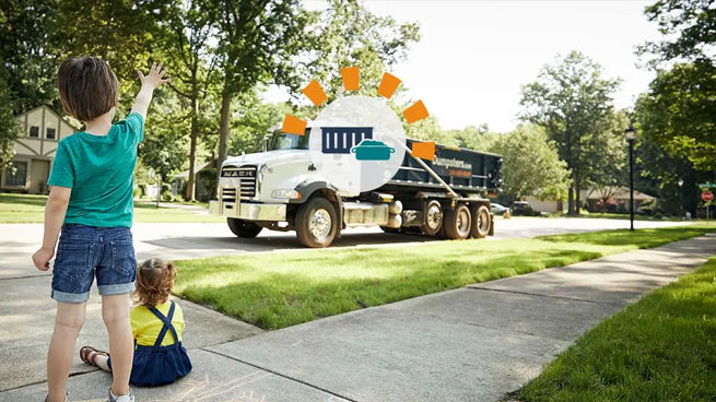 Children waving at roll off dumpster truck