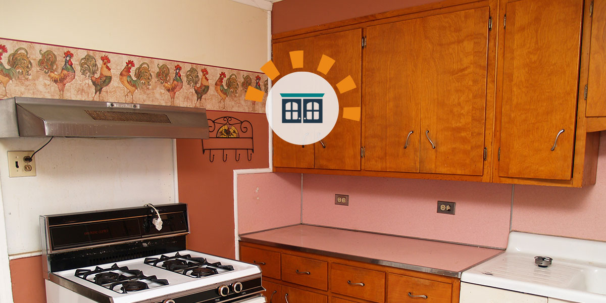 Old wooden kitchen cabinets with a salmon colored countertop and backsplash.