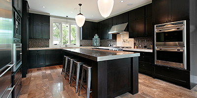A modern kitchen with black cabinets and stainless steel countertops.