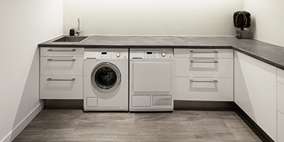 Renovated laundry room with grey cabinets and washer and dryer. 