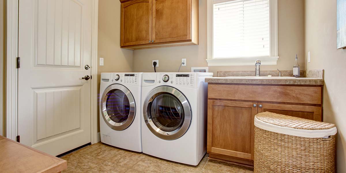 Laundry Room With White Appliances and Wood Cabinets.