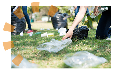 A person cleans plastic bottles, bags and other litter off a lawn.
