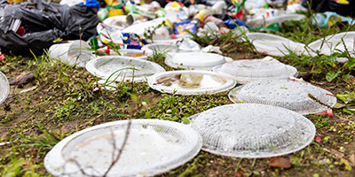 A pile of trash leaking from a garbage back onto grass.