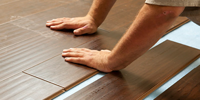 A man installing vinyl plank flooring.