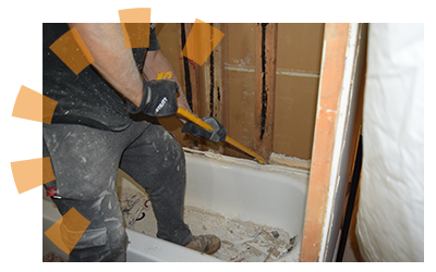 Worker man using crowbar to pry bathtub from wall.