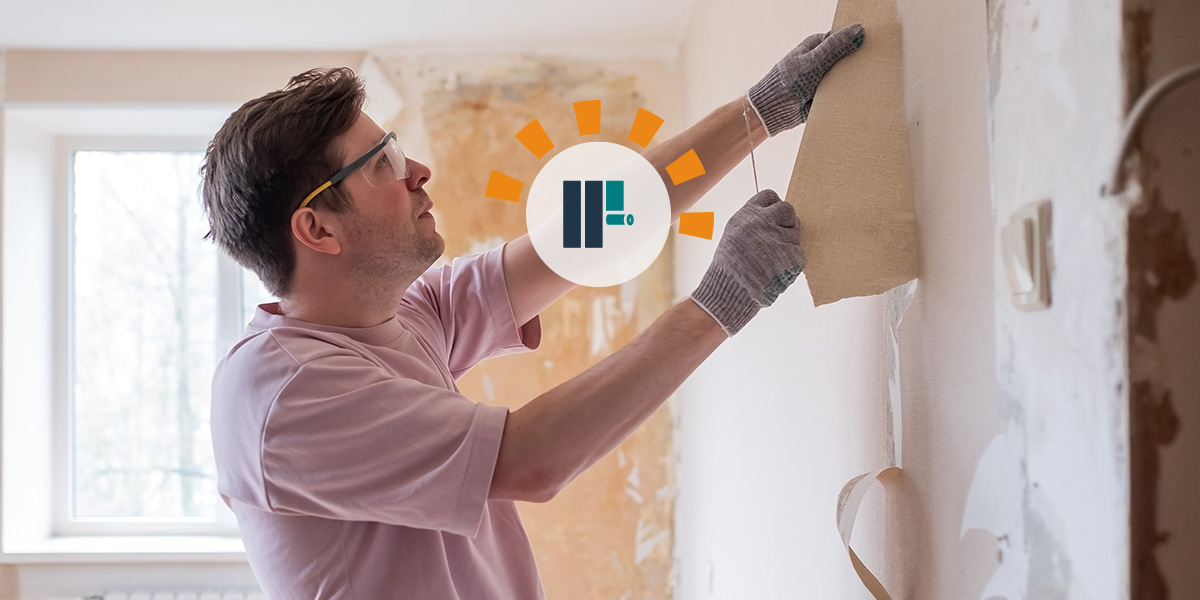 A man removing wallpaper in his home. 