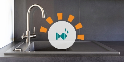 A brushed nickel kitchen faucet with black countertops.