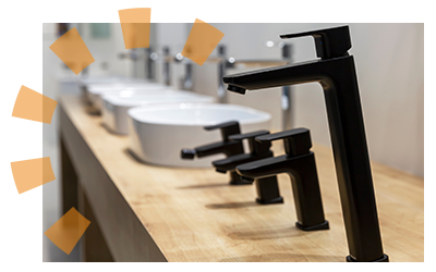 Modern black kitchen faucets lined up in a showroom with contemporary bowl sinks in the background.
