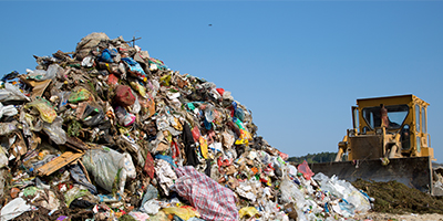 Pile of Debris in Landfill With Truck in Background.