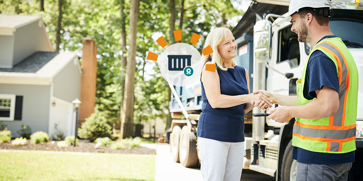 A Dumpsters.com driver shaking hands with a woman in a blue shirt after picking up a roll off dumpster. 