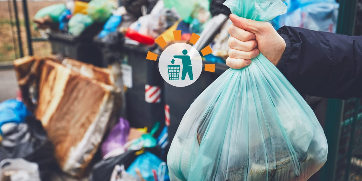 Person Holding Blue Trash Bag in Front of Piles of Garbage