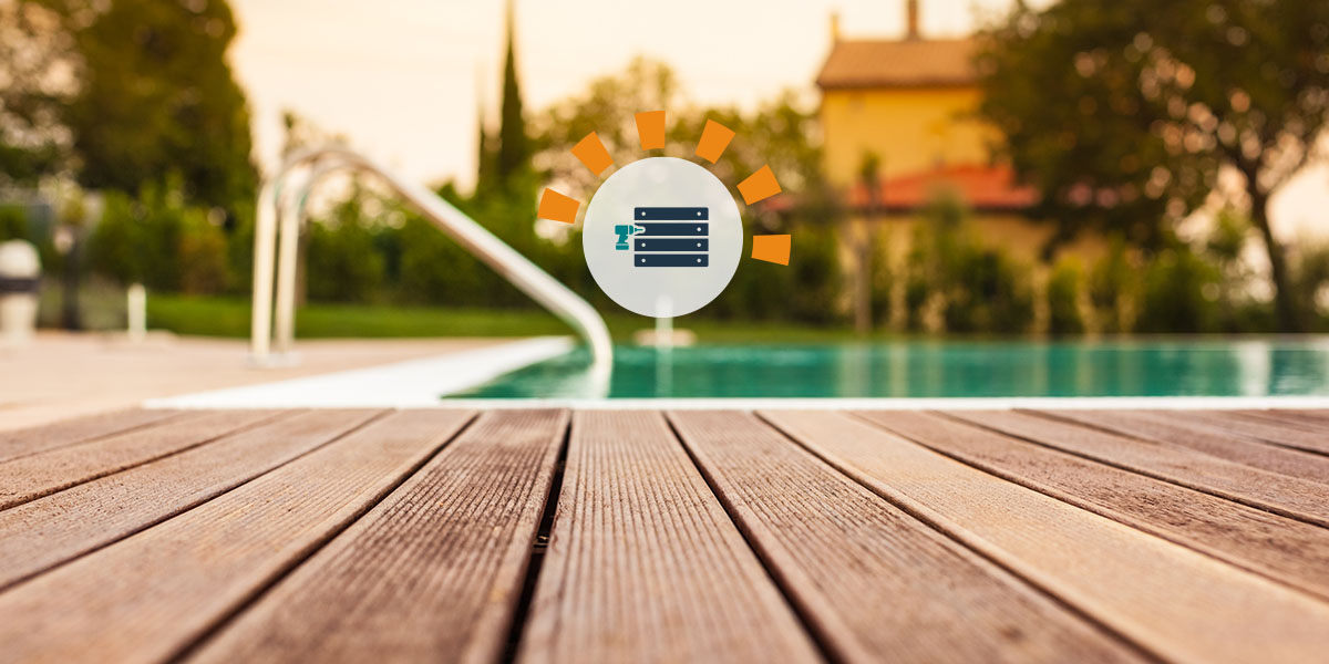 Old wooden deck in foreground with blurred pool and house in the background.