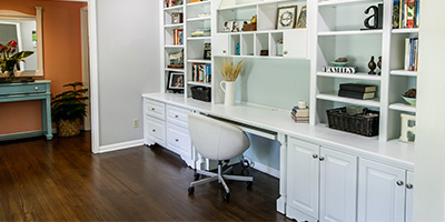 An organized and decluttered desk area featuring a wall-length white desk with white shelving to the ceiling and under cabinets and drawers.