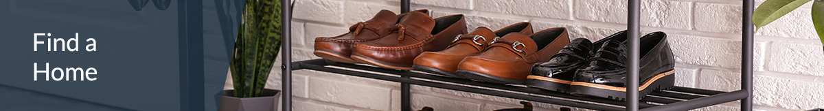 Seven pairs of shoes on a metal show rack next to a coat hangar.