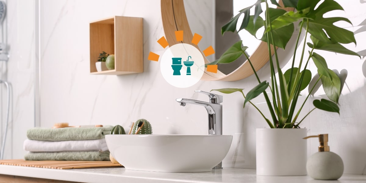 Organized bathroom sink area with a stack of towels and a plant.