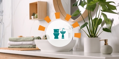 Organized bathroom sink area with a stack of towels and a plant.