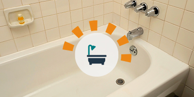 Outdated off-white plain bathtub and surrounding tile.