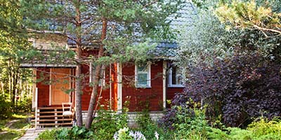 Residential property with red house and overgrown trees that need trimming and pruning in front yard.