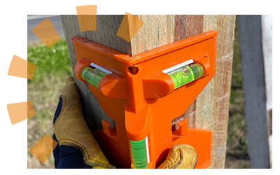 A construction worker holding a level against a wood post.