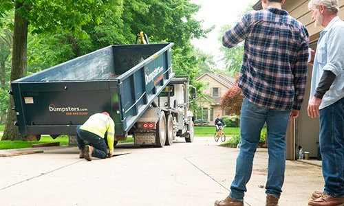 A Dumpsters.com driver placed wood planks under the wheels of a roll off dumpster during delivery.