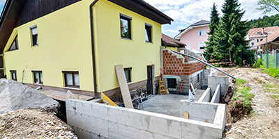 A yellow house with fresh construction building a new home addition.