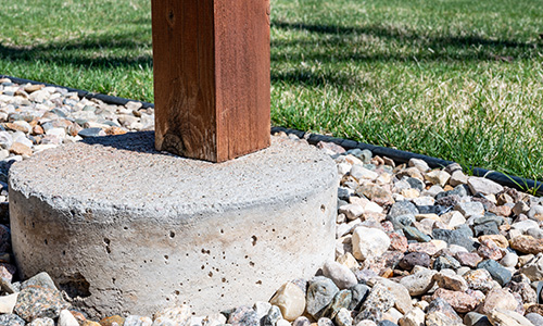 A wooden porch post in a cement footer.