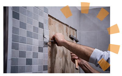 Hands hammering chisel to tear up bathroom wall tile.