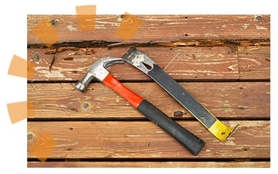 Pry bar and hammer sitting on wood deck used for removing old nails and prying up treads.