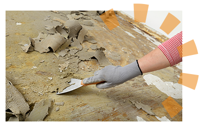 Worker scraping linoleum or vinyl adhesive glue remaining beneath the old floor.