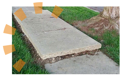 A raised slab of sidewalk with dirt underneath it. 